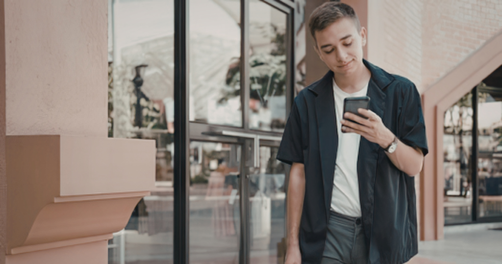 Person walking outside hotel while looking at phone, highlighting hotel safety tips Las Vegas and the importance of situational awareness and avoiding distractions